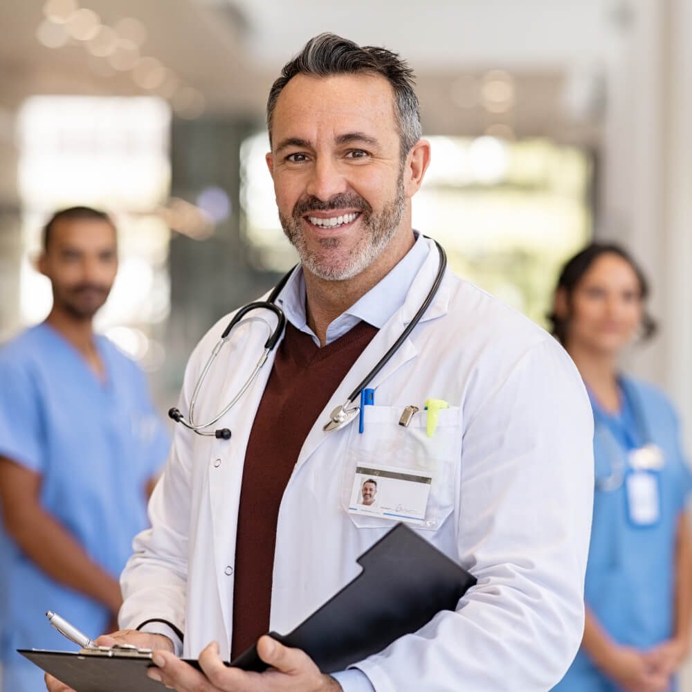 Doctor smiling at Camera with Team