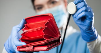 Female doctor holding empty red wallet with stethoscope