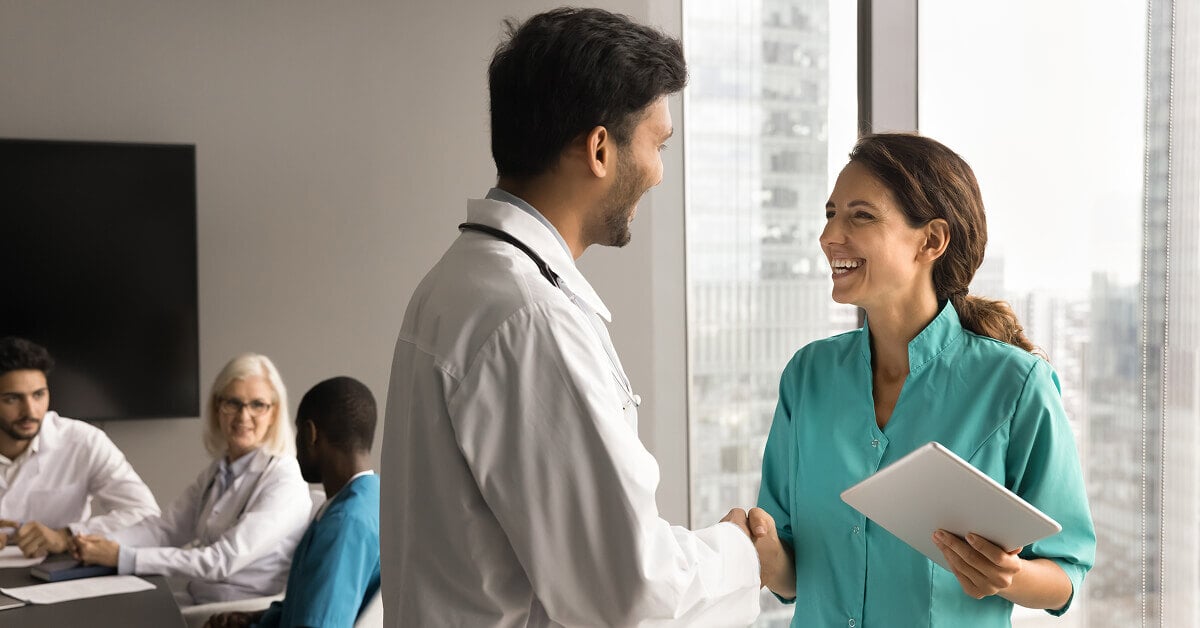 Doctor shaking hands with female insurance payor rep after negotiation